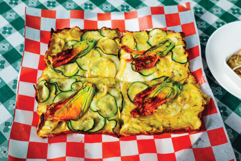 Pizza with slices of squash and squash leaves