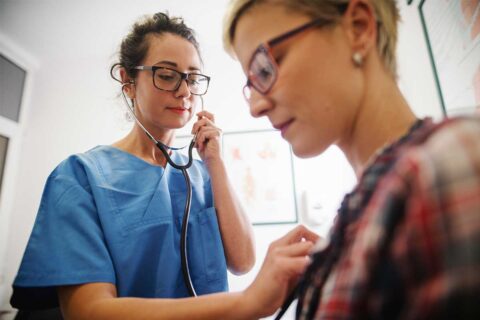 doctor checking women's heart with stethoscope