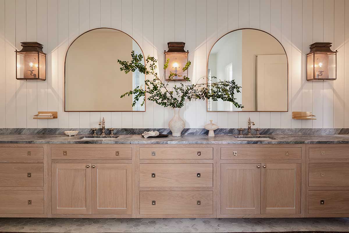 double vanity with arched mirrors and light wood cabinets