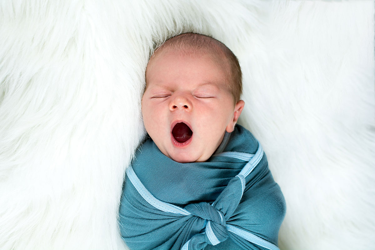 newborn baby wrapped in teal blanket