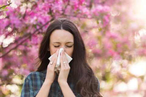 woman blowing nose outside