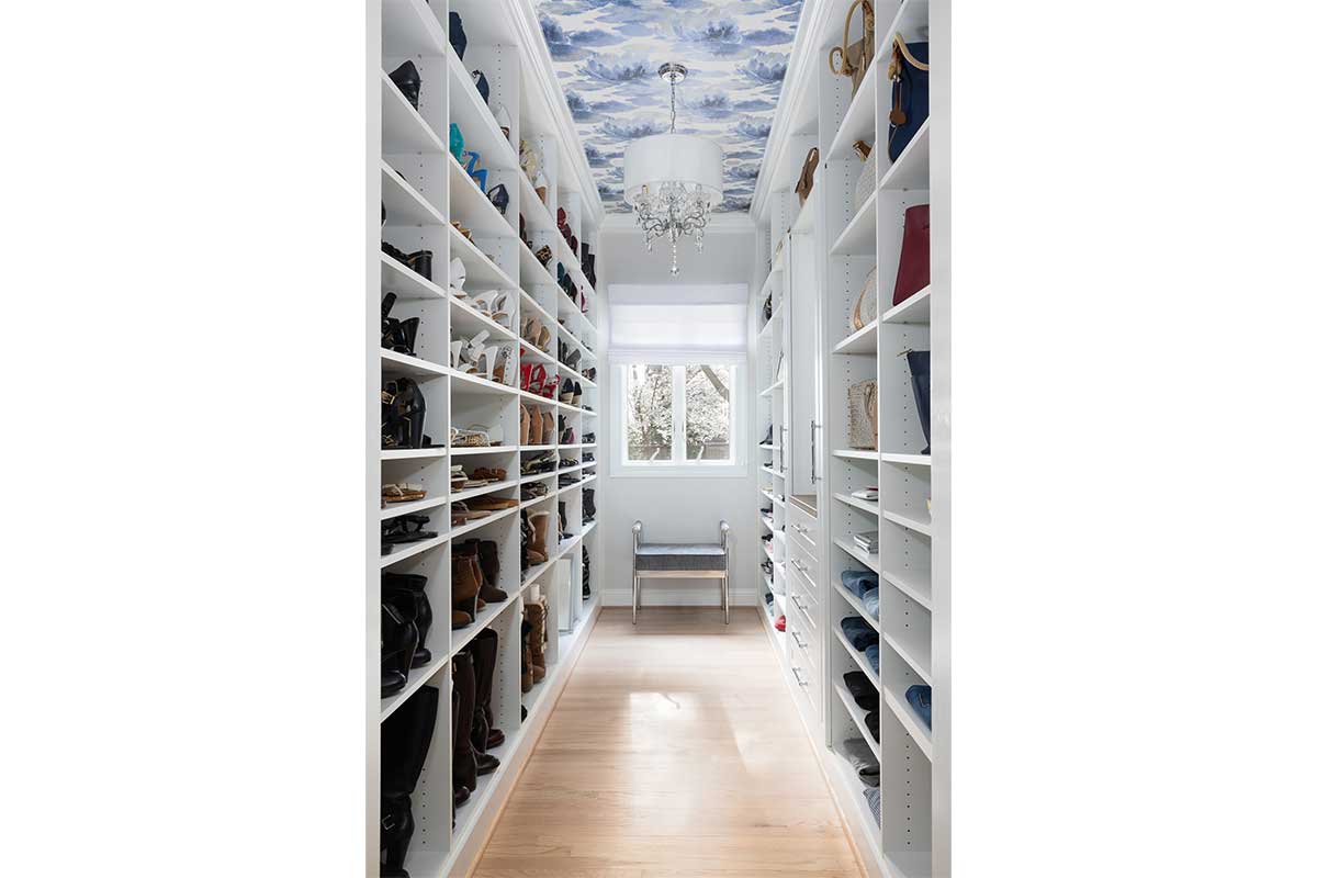 closet with built in shelves and wallpaper ceiling