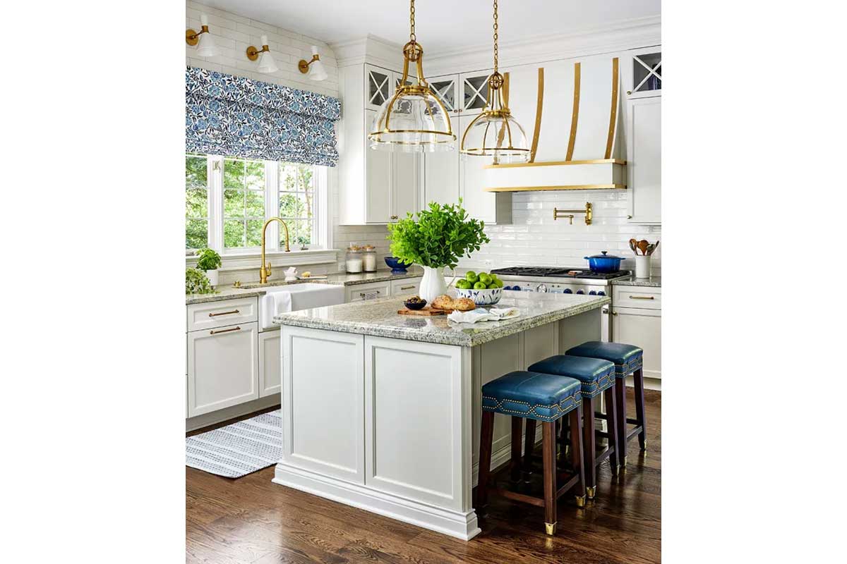white kitchen with island, gold accents and patterned fabrics