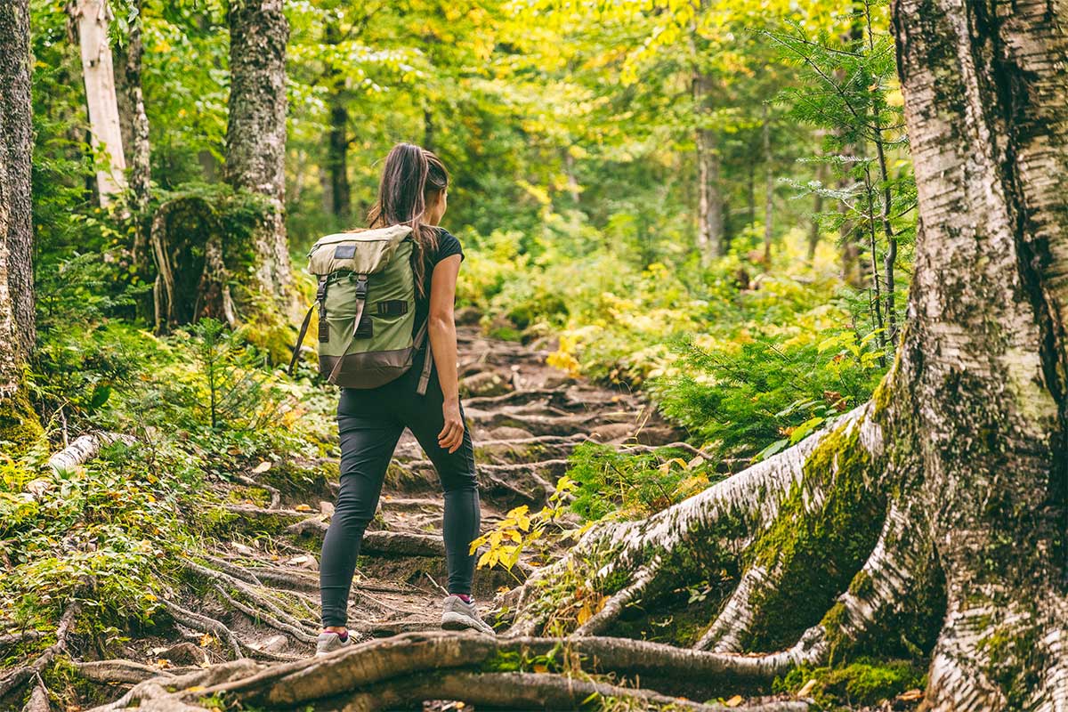 woman with backpack hiking in forest