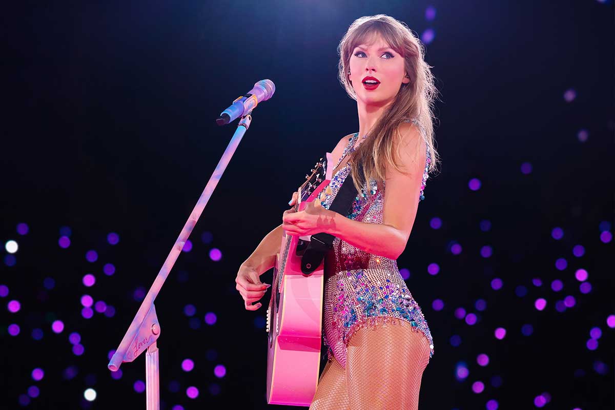 Taylor Swift performing at Eras Tour with pink guitar