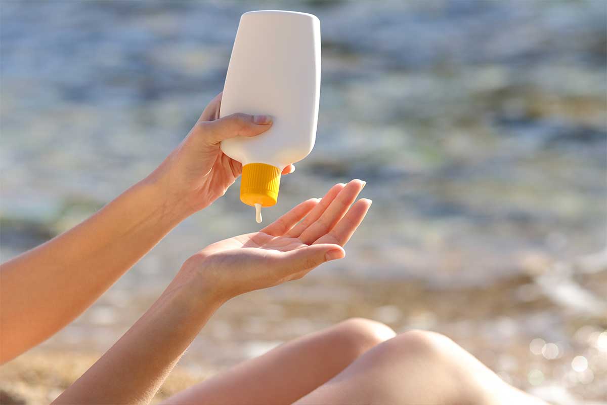 person squeezing sunscreen bottle