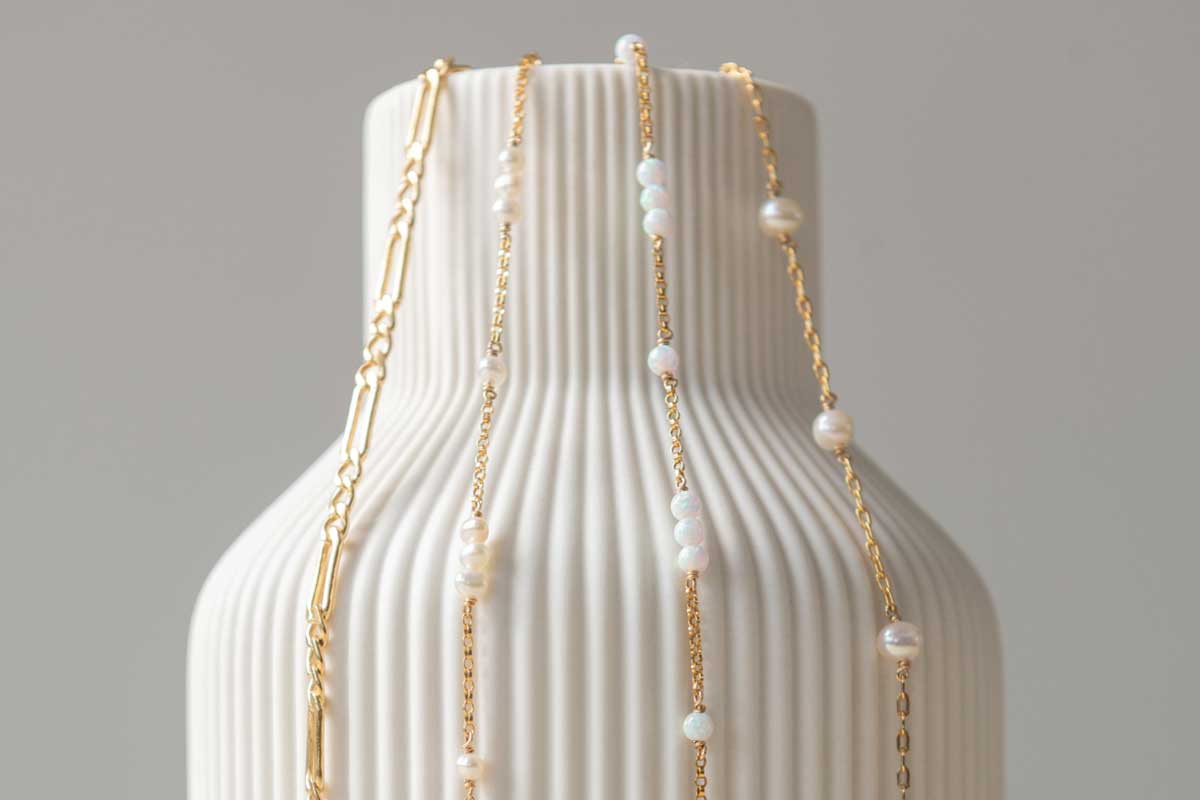 gold bracelets with pearls hanging from vase