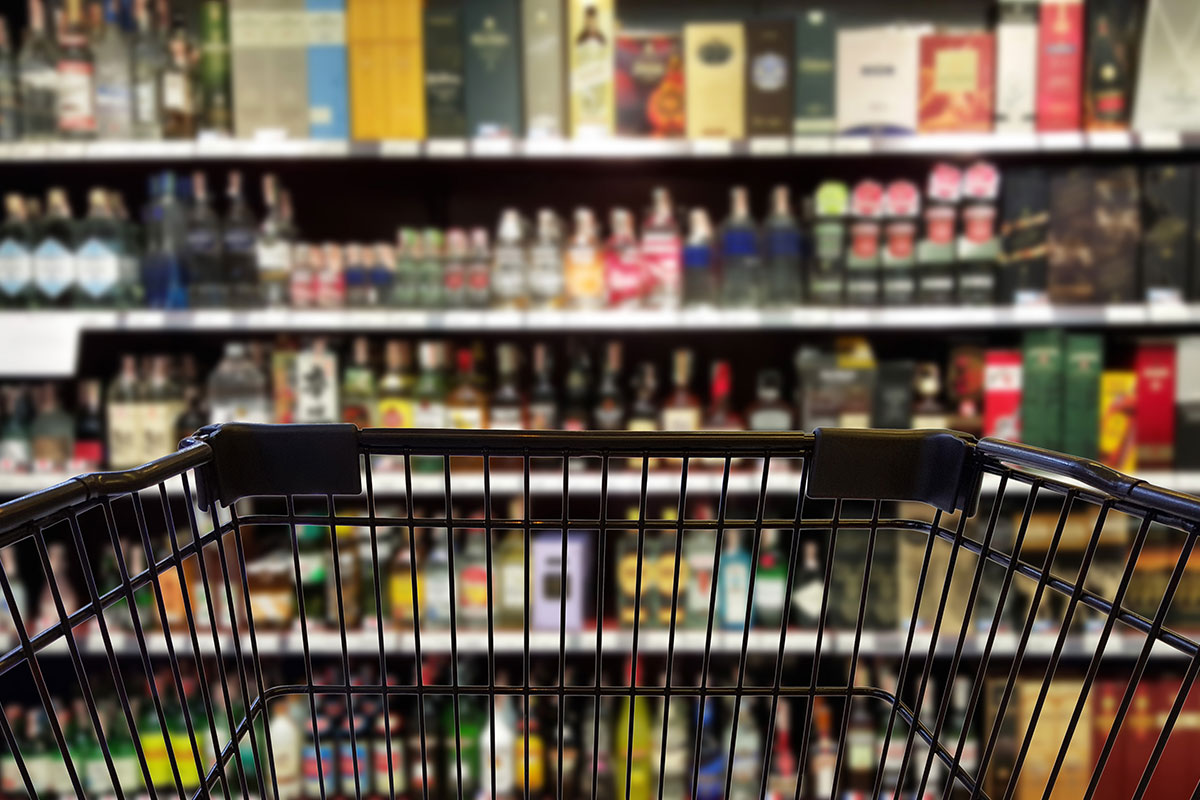 Shopping cart in from of alcohol in store