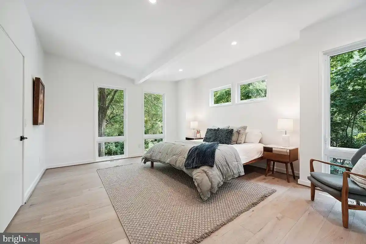 primary bedroom with wood floors and view of trees at 7318 Rippon Rd.