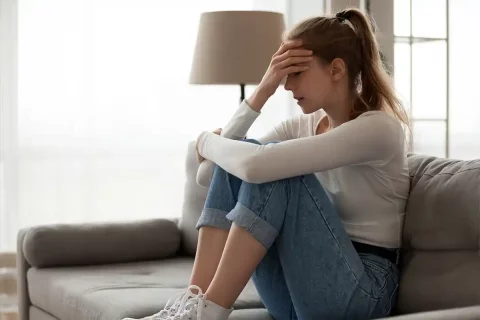 woman sitting on couch with knees to chest