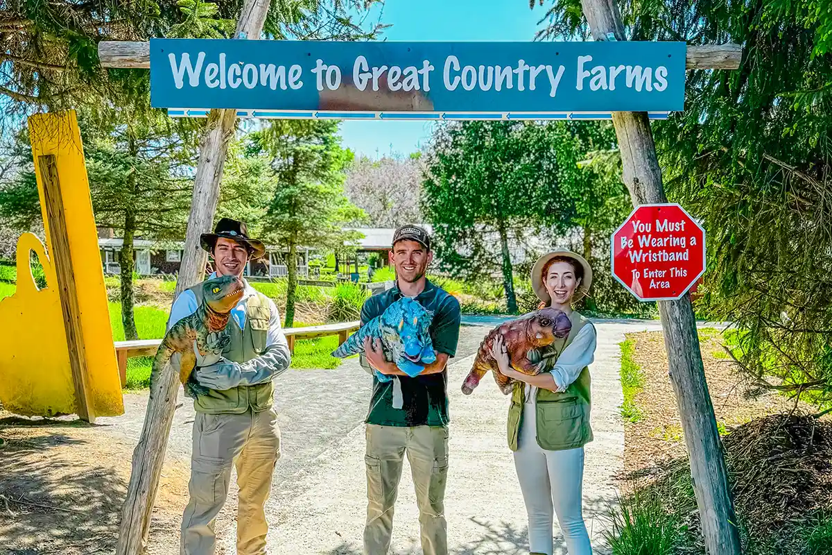 three people holding baby dinosaur puppets at great country farms