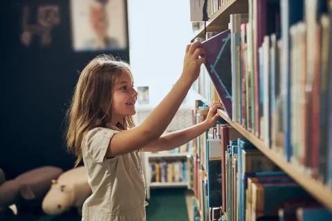 girl picking out library book