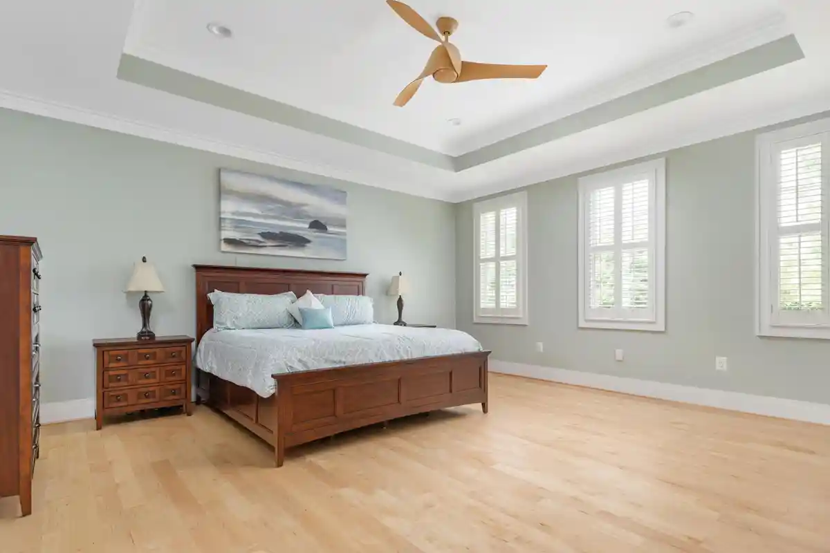 primary bedroom with light green walls and tray ceiling