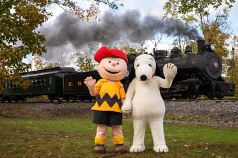 charlie brown and snoopy mascots in front of train