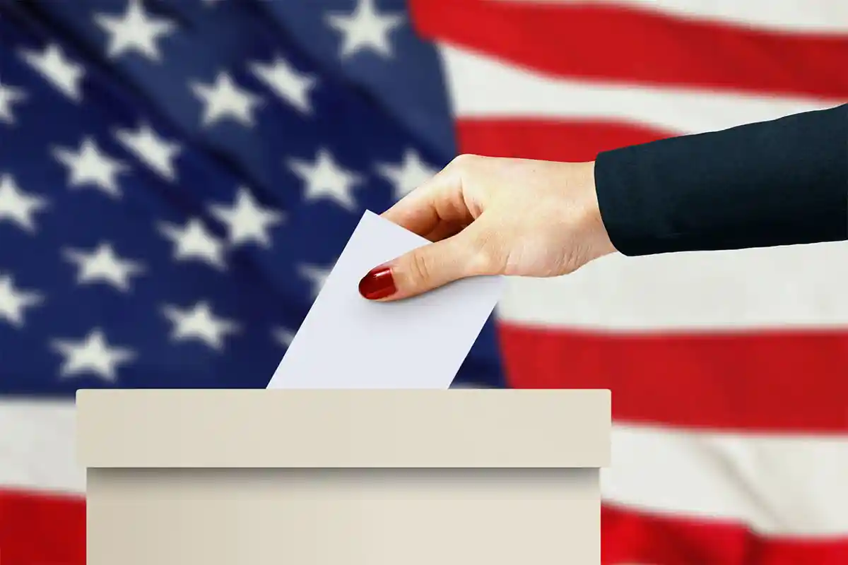 Woman's hand drops ballot into box