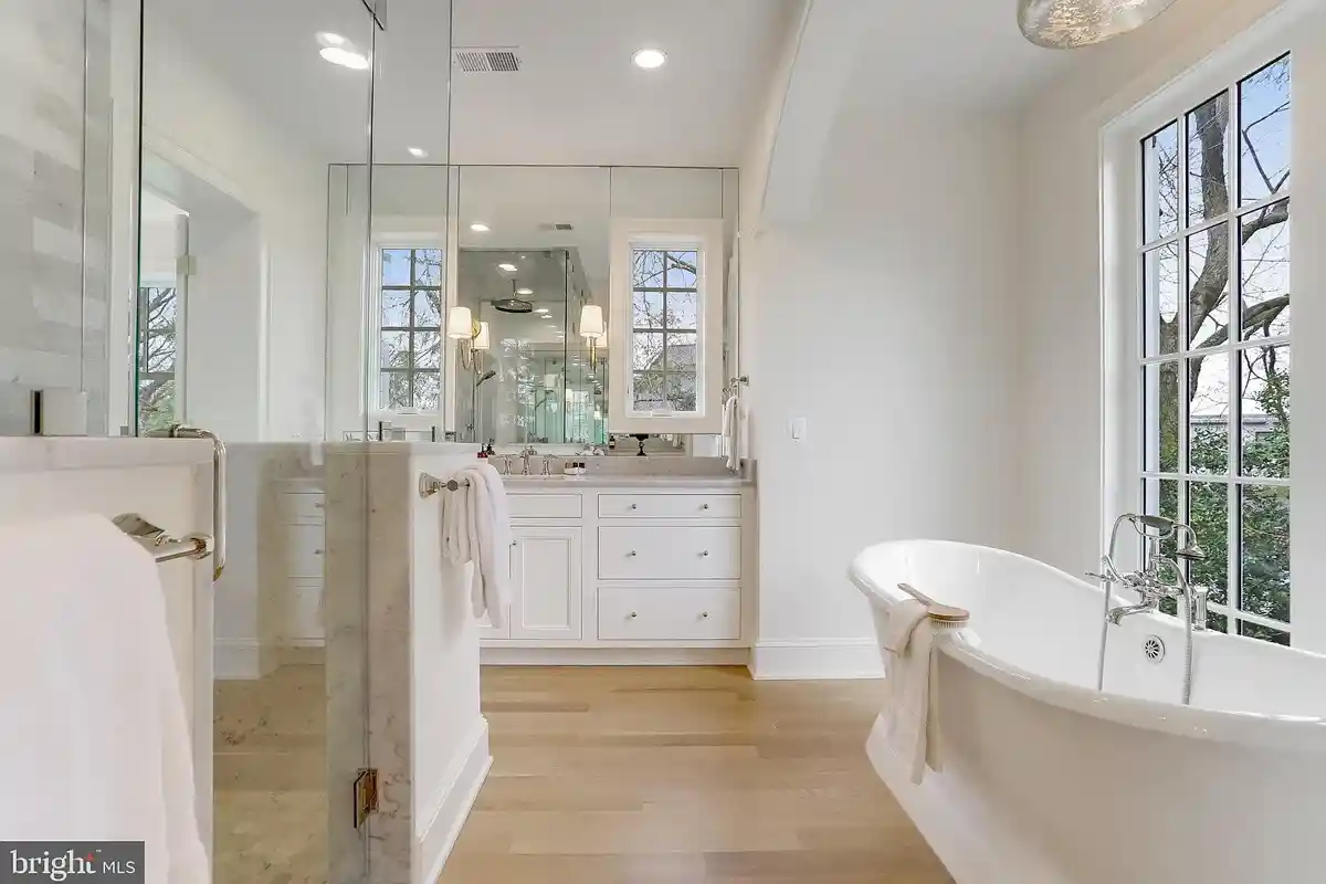owner's bathroom with white walls, standalone tub, and steam shower