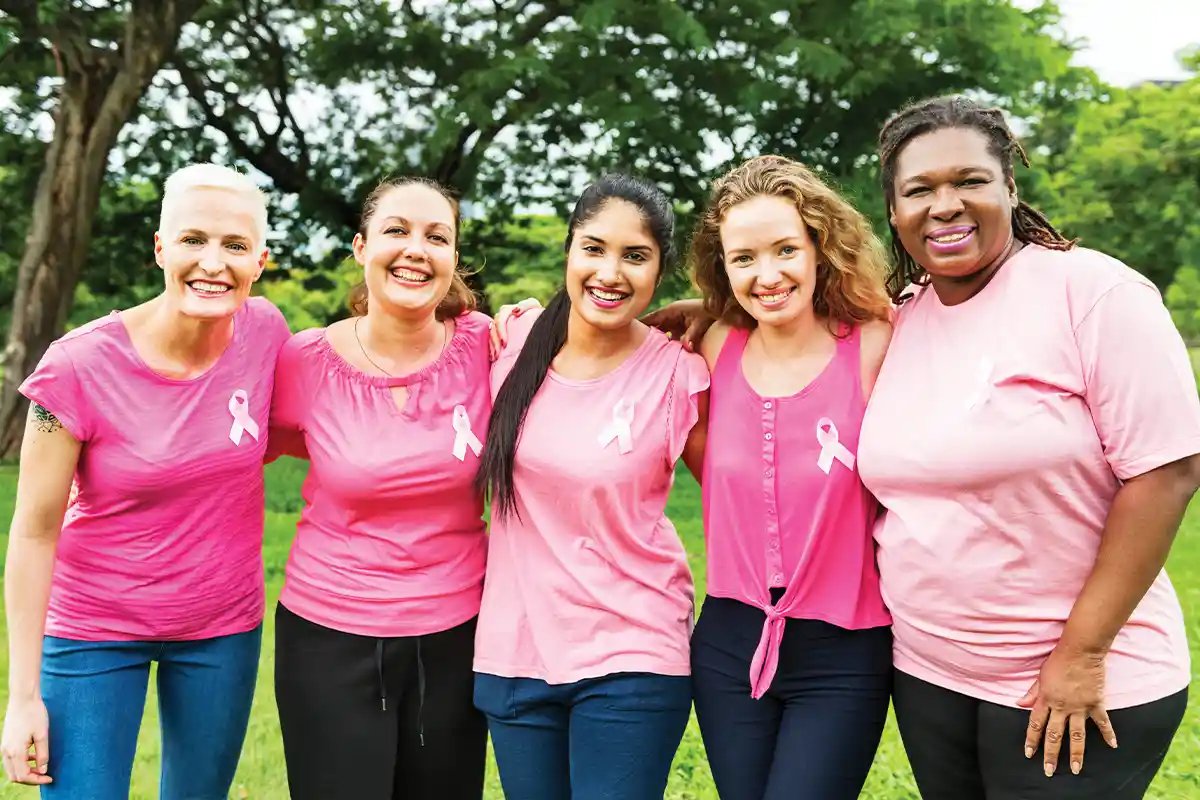 five women wearing pink shirts and breast cancer ribbons