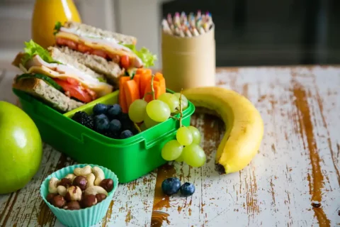 healthy school lunch with a sandwich, nuts, and fruits