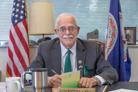 Congressman Gerry Connolly sits at a desk with a U.S. and Virginia flag in the background