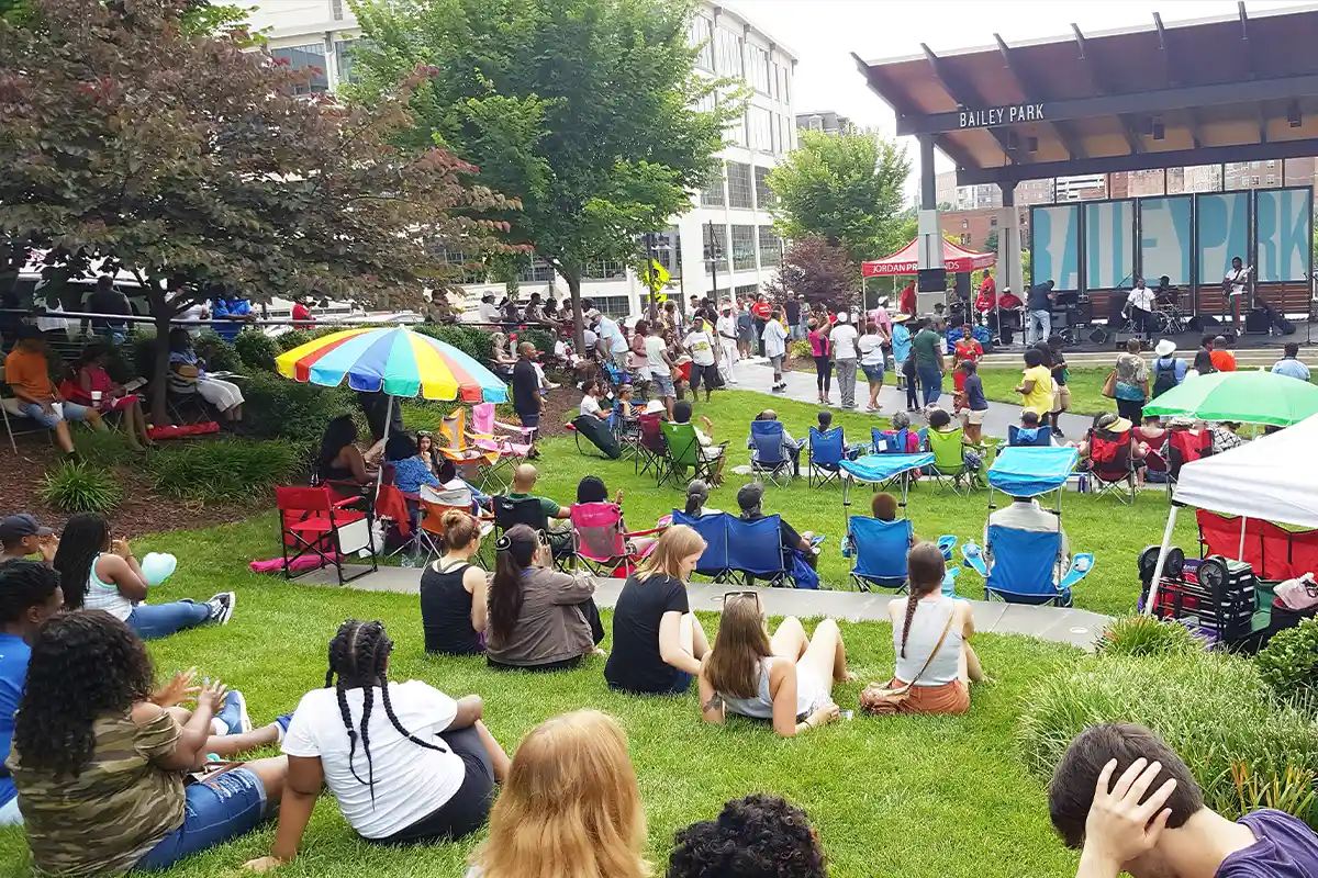 crowd sitting on grass at bailey park
