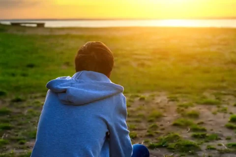 lonely guy, possibly with depression, looking at sunset