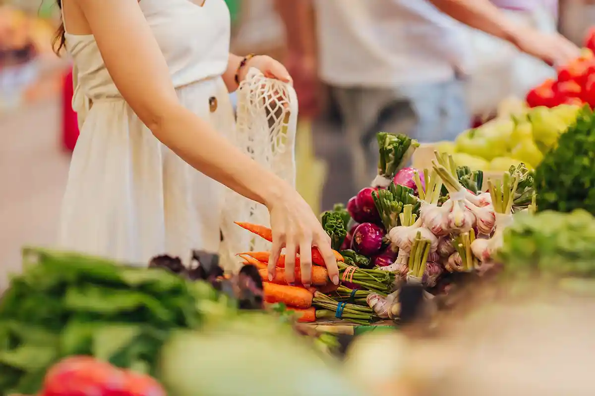 woman picking up carrots at farmers market