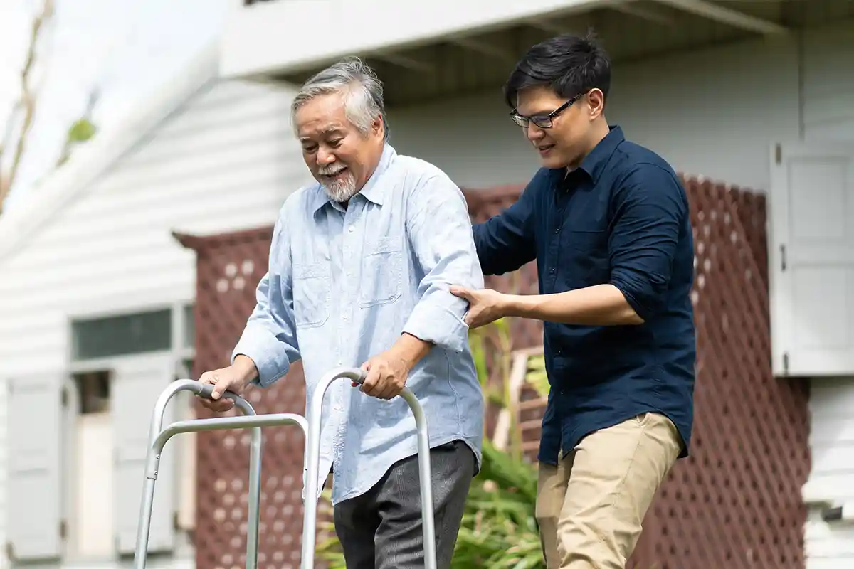 man helping senior man with his walker