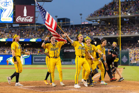 Savannah Bananas players hold up an American flag on a baseball field