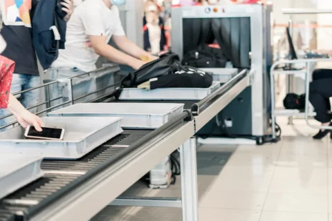 People place items in bins at airport security checkpoint. Two major airports serving DMV set new records for the number of guns found at TSA checkpoints last year.