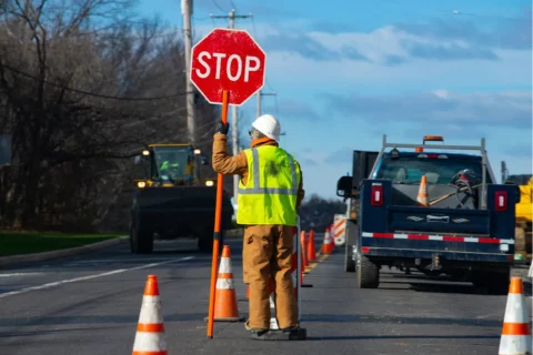 Construction worker holds stop sign in road under construction