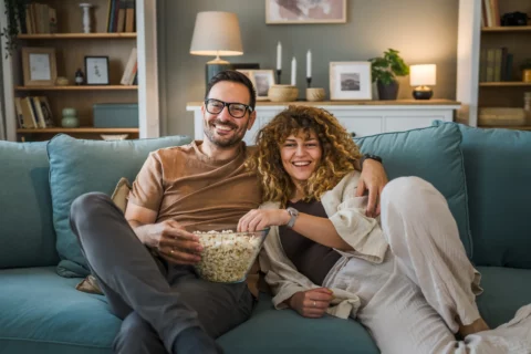 Couple watching TV and eating popcorn on a couch