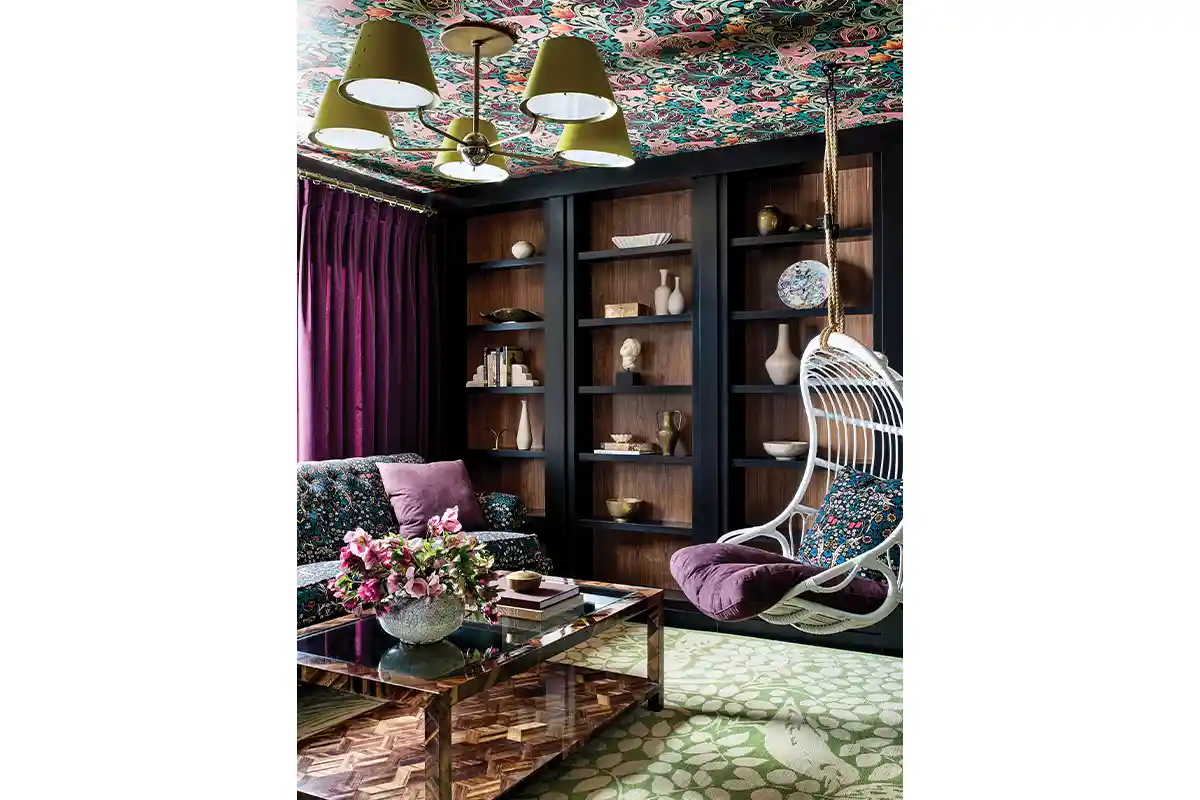 room with bookcase, hanging chair, and wallpapered ceiling