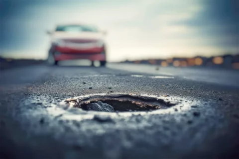 car driving toward a pothole