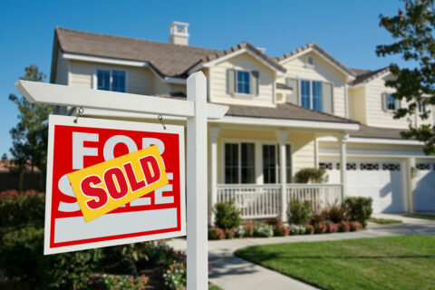 a Sold real estate sign in front of a house