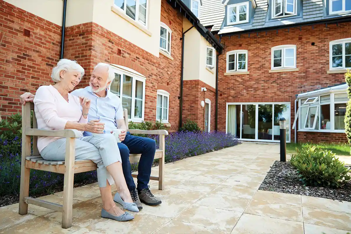 senior couple sitting on a bench outside of building