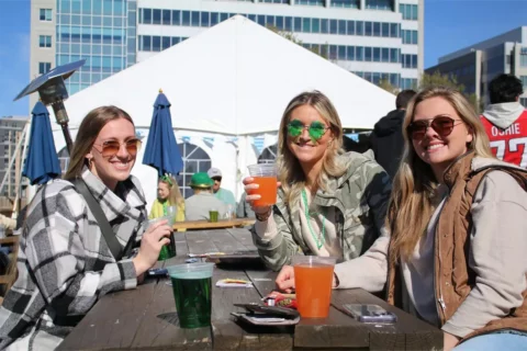 3 women sit at a table with St. Patrick's Day drinks