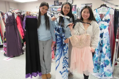 FCPS Students Marianna Martinez, Ananyah Tines, Kaila Le hold dresses at the Centreville High School Prom Dress Shop