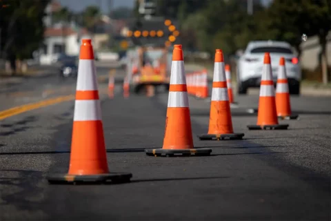 traffic cones lined up a road in front of an arrow directing traffic