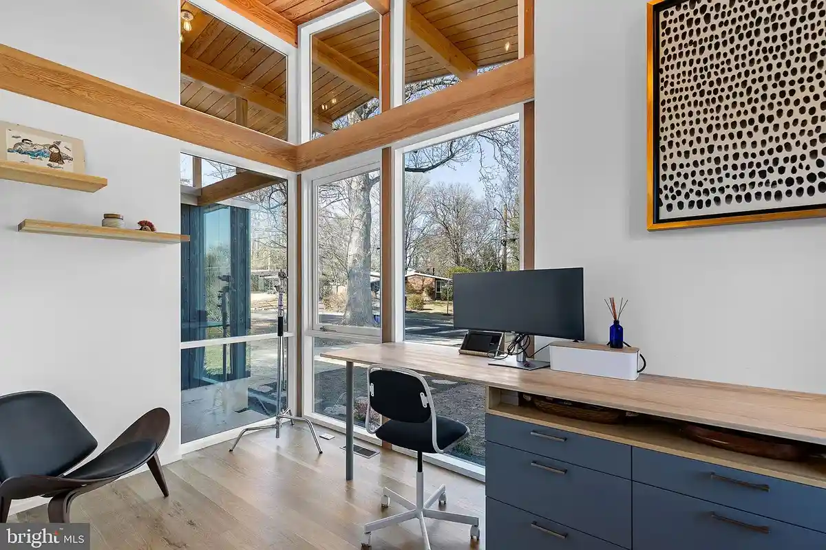 office with built-in desk and windows that look out to entryway of home