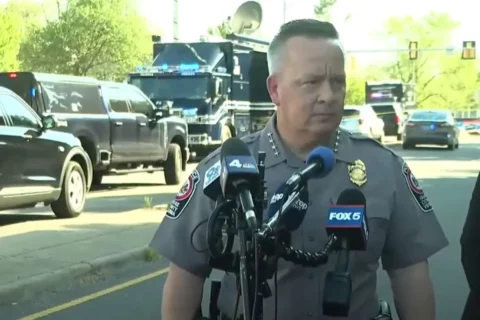 Fairfax County Police Chief Kevin Davis stands in the road speaking into microphones during a news conference.