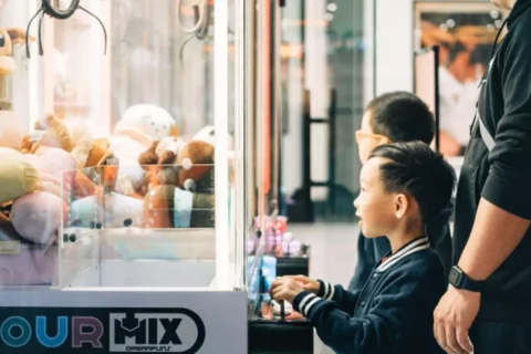 a child in a NJ Gatcha store plays at a claw machine trying to win a stuffed animal
