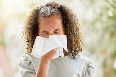 Girl sneezing into tissue