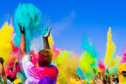 A man throws blue colored powder into the air at a Holi Festival of Colors celebration