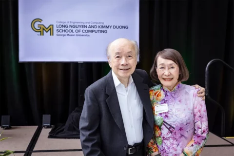 Long Nguyen and Kimmy Duong stand in front of a sign announcing George Mason University's Long Nguyen and Kimmy Duong School of Computing