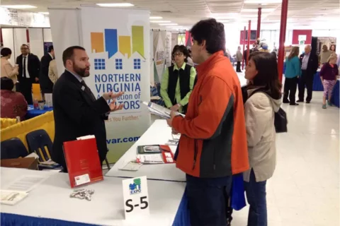 people talk on either side of a table at the Northern Virginia Housing Expo