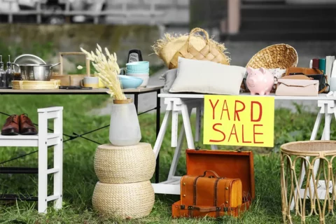 Items on a table and lawn with a yard sale sign