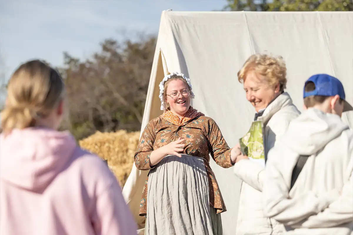 women in colonial clothing speak outside of tents at a Mount Vernon encampments
