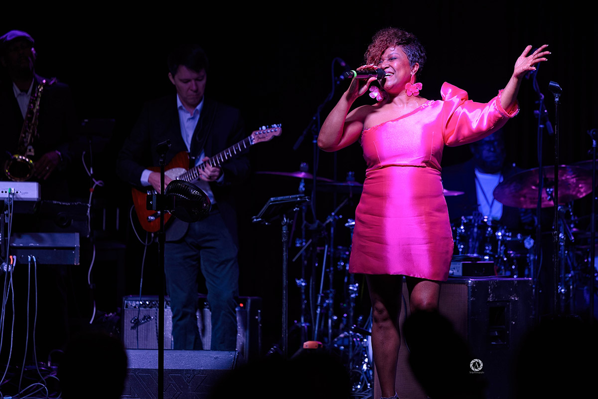 tracy hamlin singing on stage in a pink dress