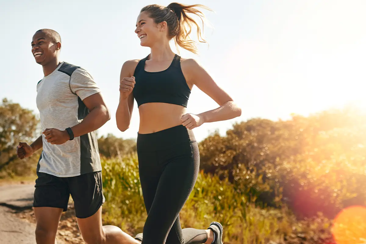 a man and a woman smiling while on a trail run