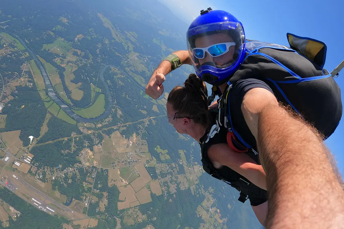 Two tandem skydivers in the air looking down below